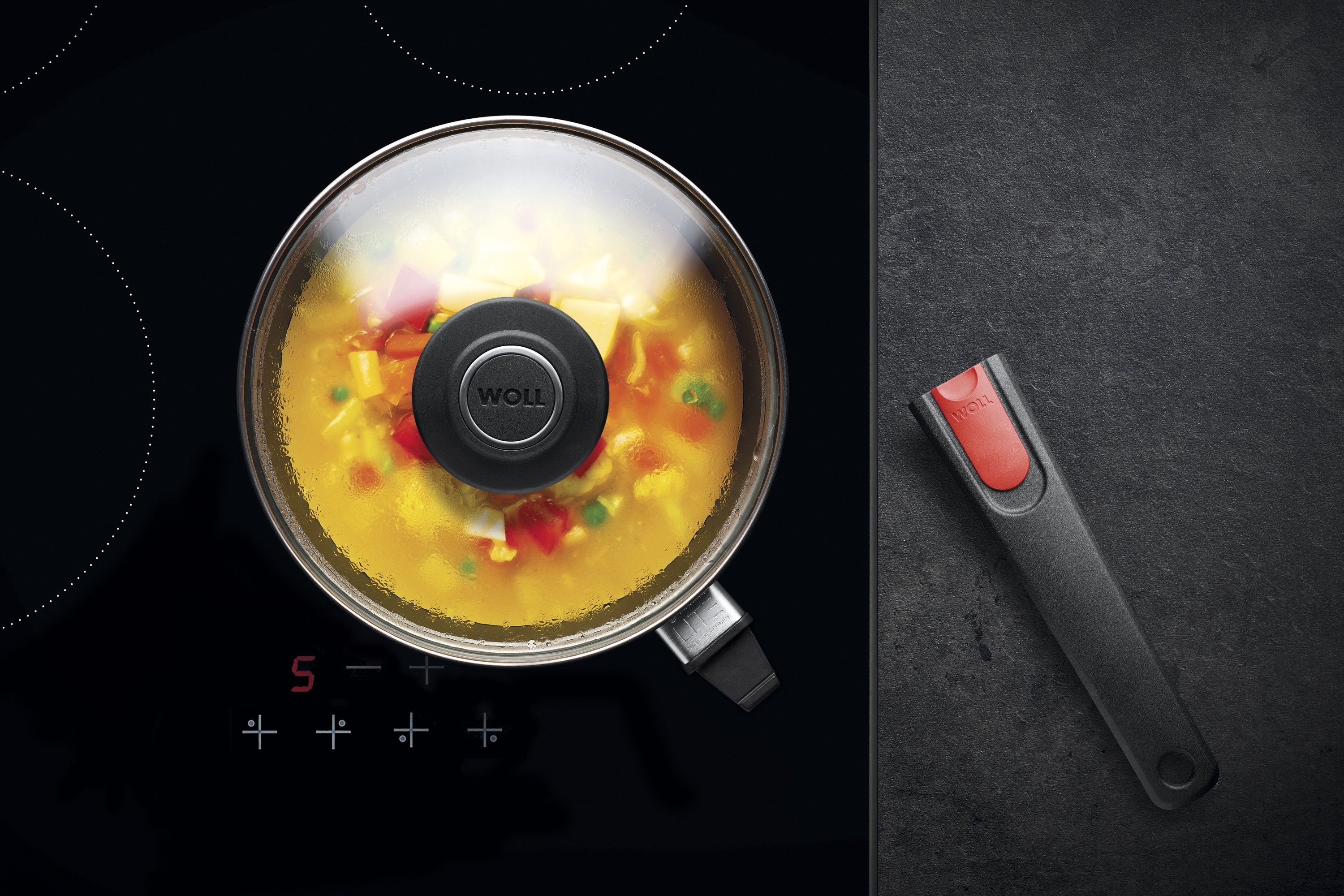 Auf dem Herd steht eine runde Diamond-Lite-Pfanne mit abgenommenem Stiel, in der ein Gericht zubereitet wird. Am Glasdeckel hat sich Kondenswasser gebildet.