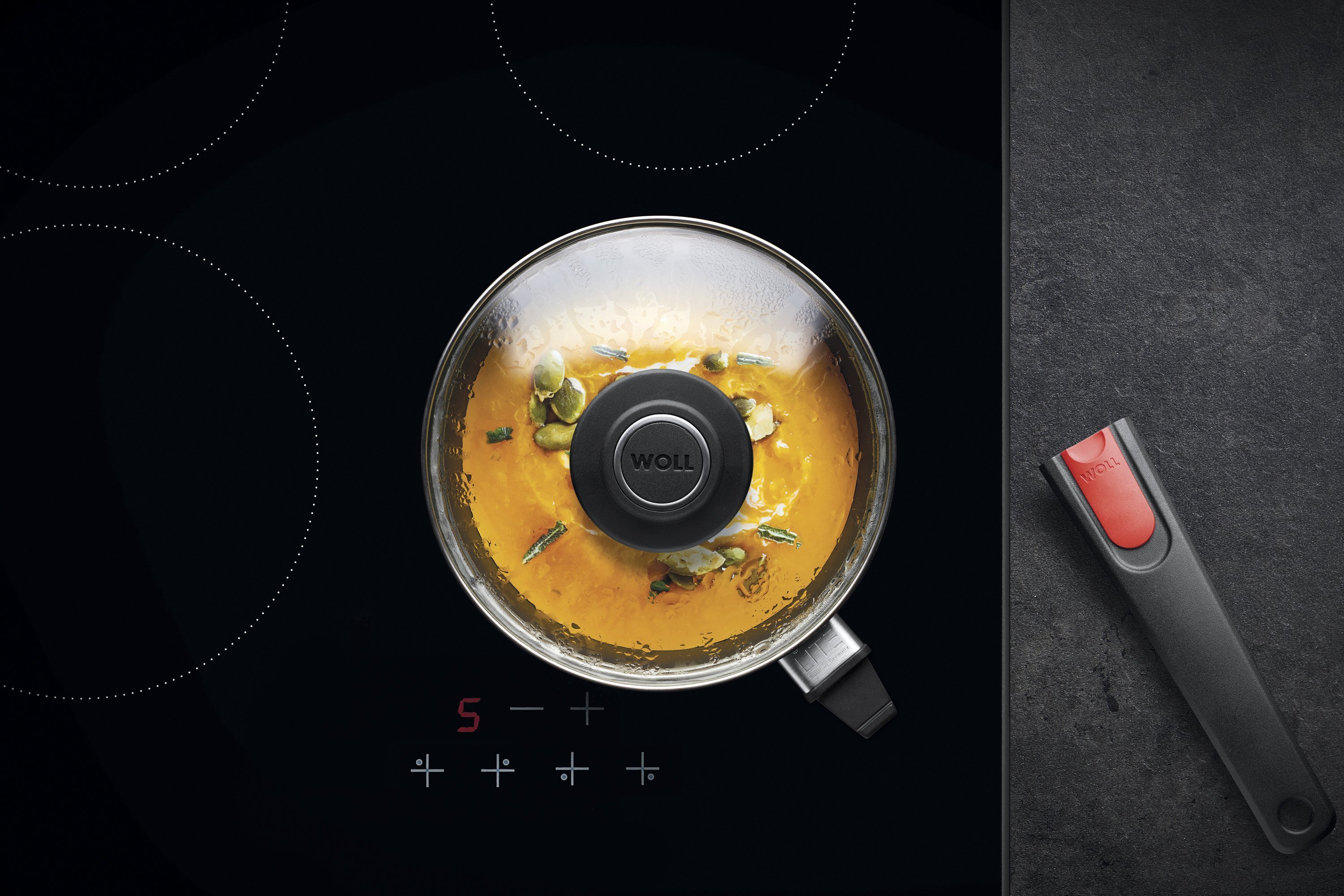 Auf dem Herd steht ein runder, heißer Stieltopf aus der Serie Diamond Lite mit abgenommenem Stiel. In diesem befindet sich ein  frisch zubereitetes Gericht. Am Glasdeckel hat sich Kondenswasser gebildet.