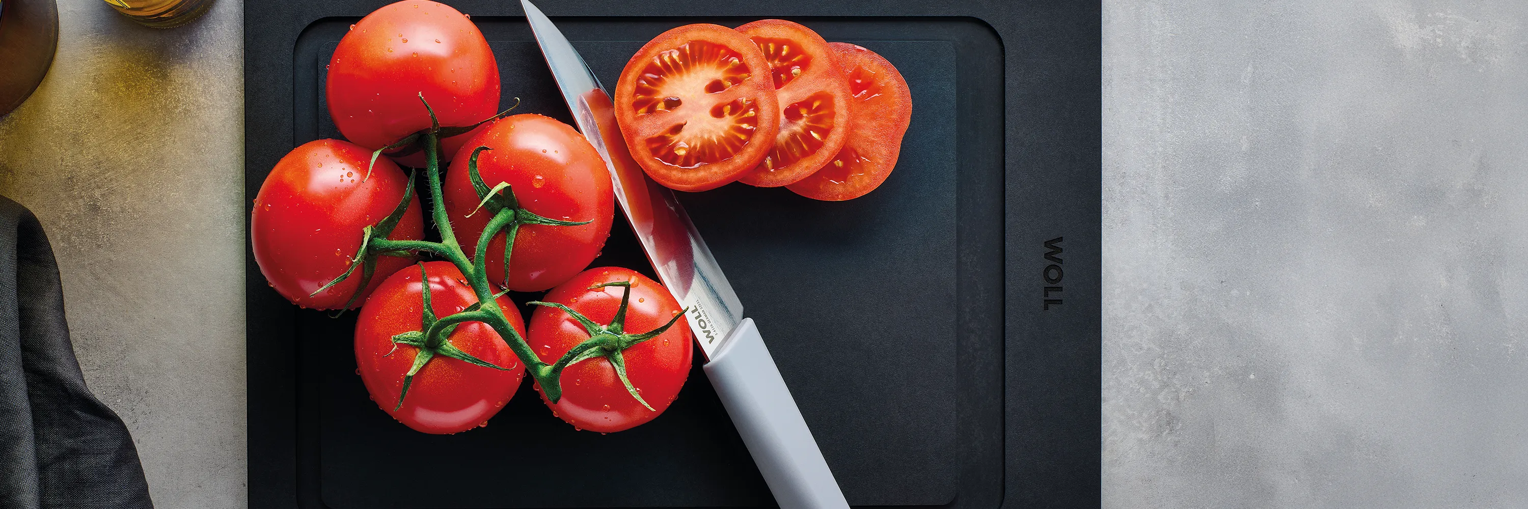 Mit dem Messer der Serie Cutting Edge werden mehrere Cherrytomaten auf einem Schneidebrett der Serie Cut & Serve halbiert.