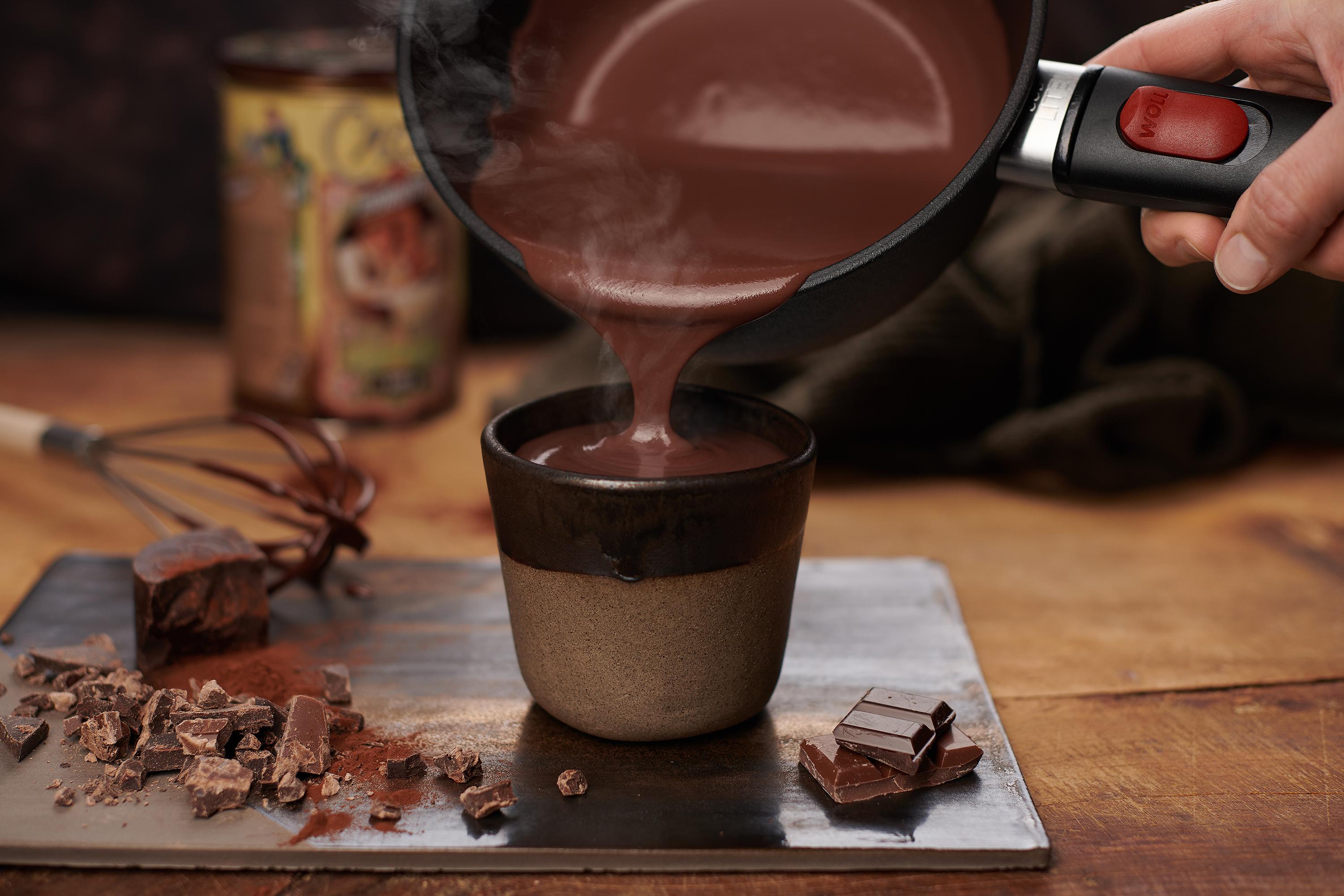 Aus einem runden Eco Lite Stieltopf wird heiße Trinkschokolade in eine Tasse gefüllt.