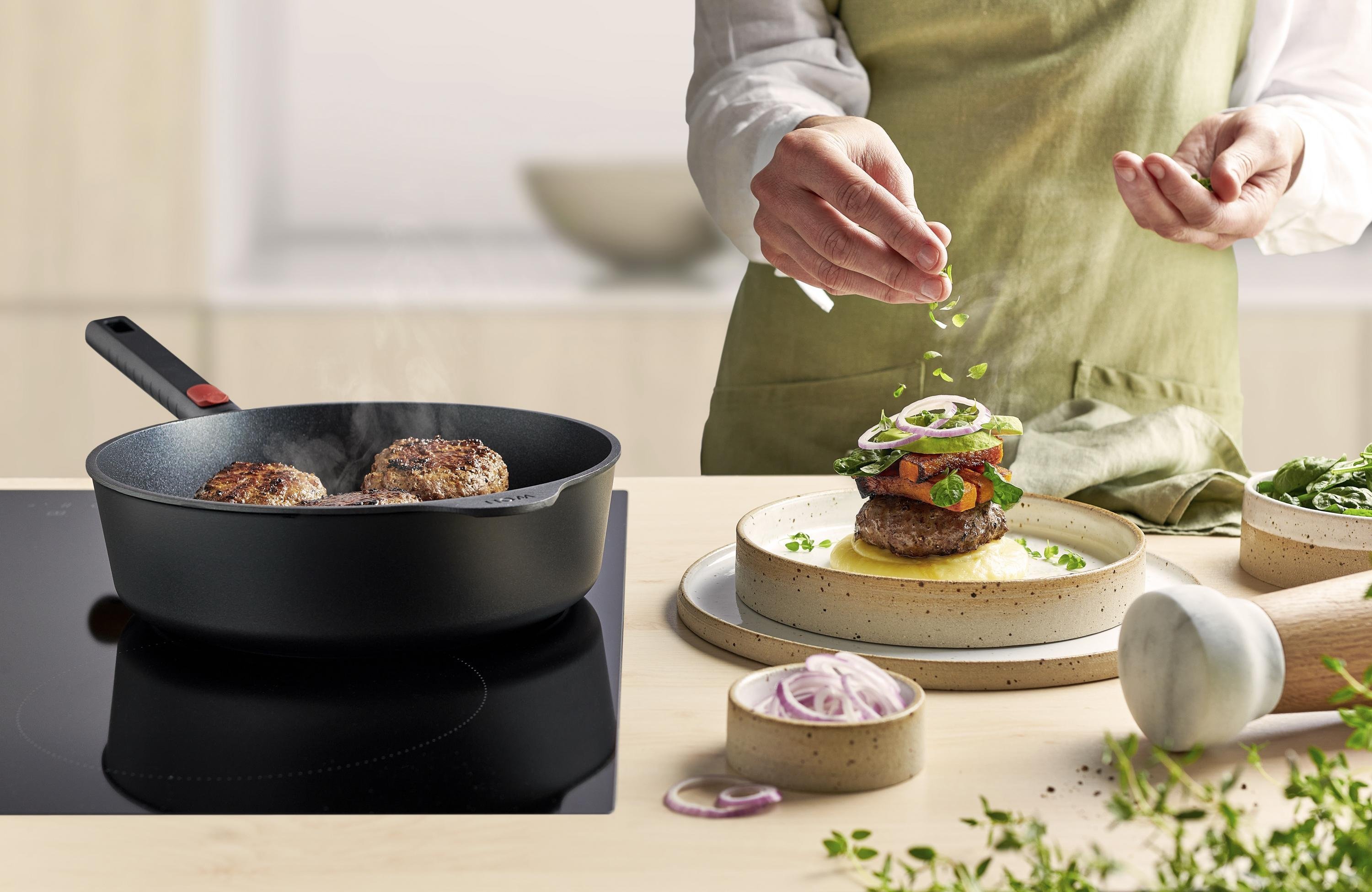 In einer runden Eco Logic QXR Pfanne werden Frikadellen angebraten und auf einem Teller platziert.