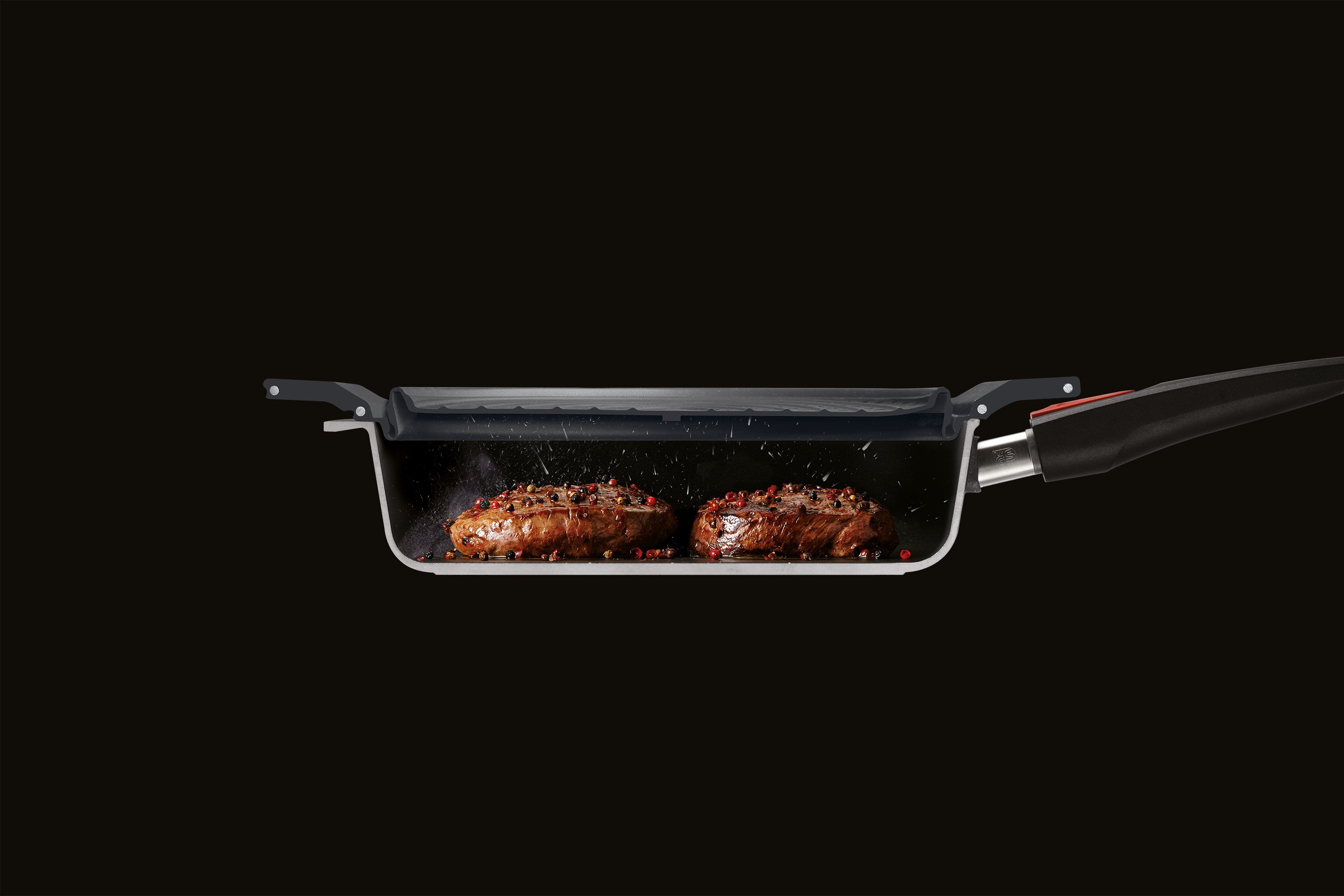 SI24F_splatter Im Querschnitt ist eine halbierte Pfanne zu sehen, in der zwei Stücke Fleisch angebraten werden. Der Steam it multifunktionale Silikoneinsatz dient als Spritzschutz.