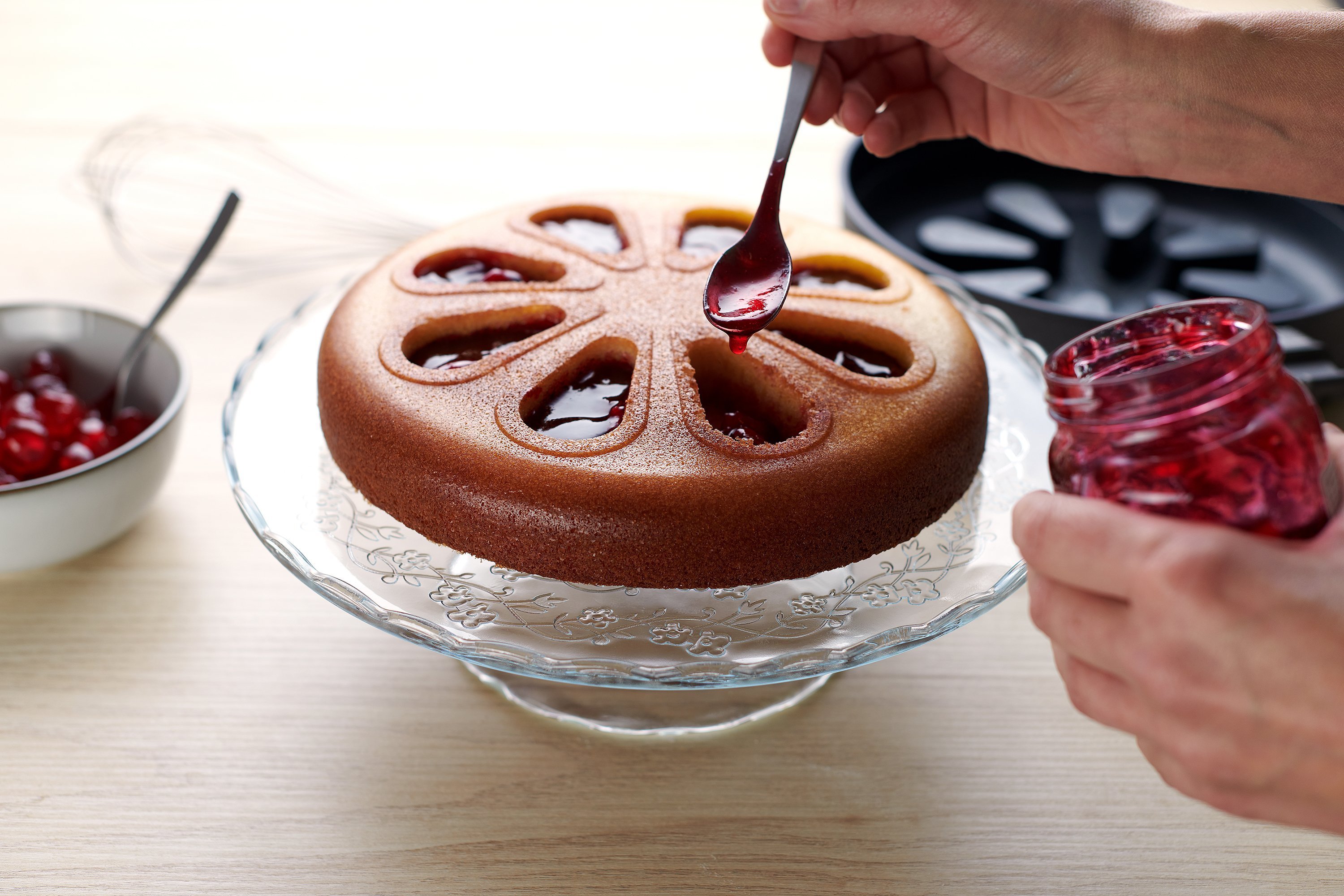 In die Vertiefungen des Kuchens wird Marmelade gegeben. Im Hintergrund ist eine runde Diamond-Lite-Pfanne mit Silikon-Backeinsatz zu sehen.