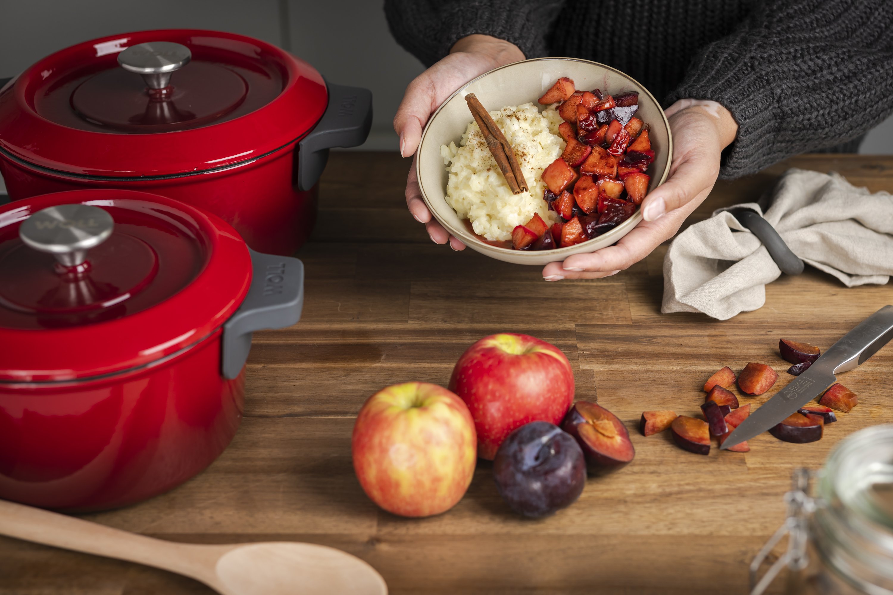 Auf der Arbeitsplatte stehen zwei runde, rote Iron-Töpfe mit Deckel. In einer der Schüsseln befindet sich ein Milchreisgericht.