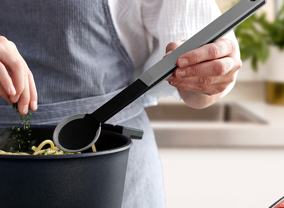 In einem Diamond Lite Topf werden frisch gekochte Nudeln mit einem grauen Kochlöffel  der Serie Cock it umgerührt und mit Kräutern garniert.