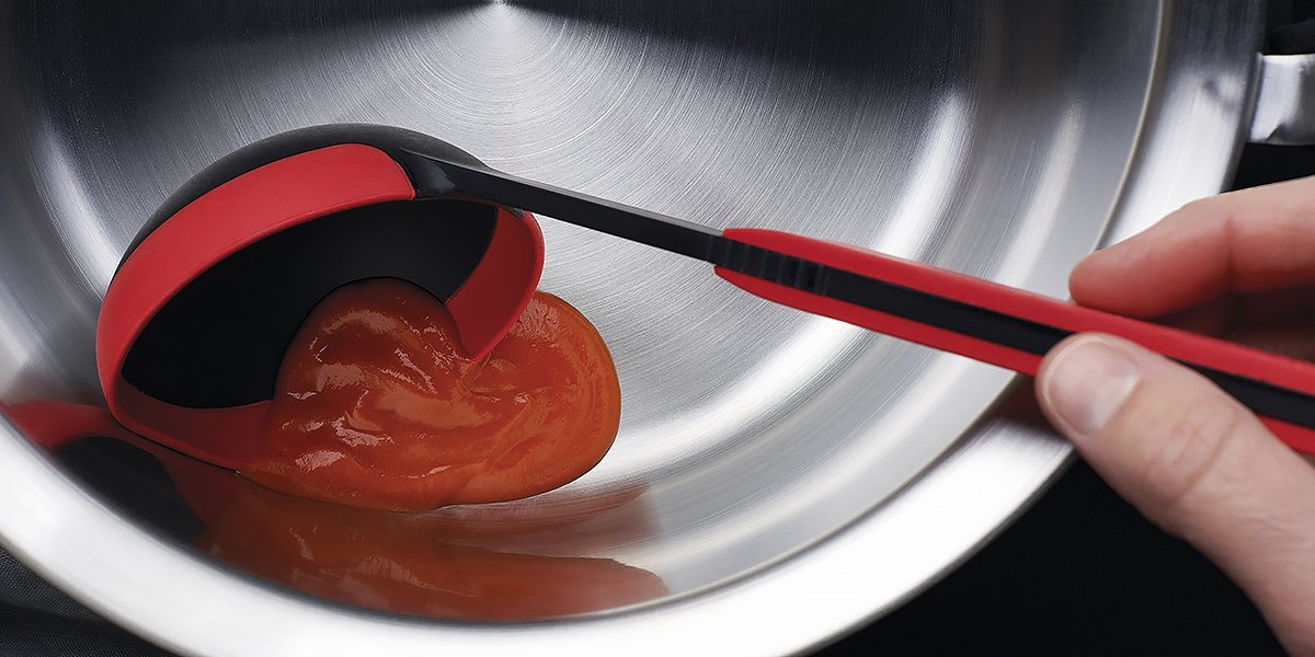 Die Tomatensoße wird mithilfe der roten Cock it Schöpfkelle in eine silberne Schüssel gegeben.