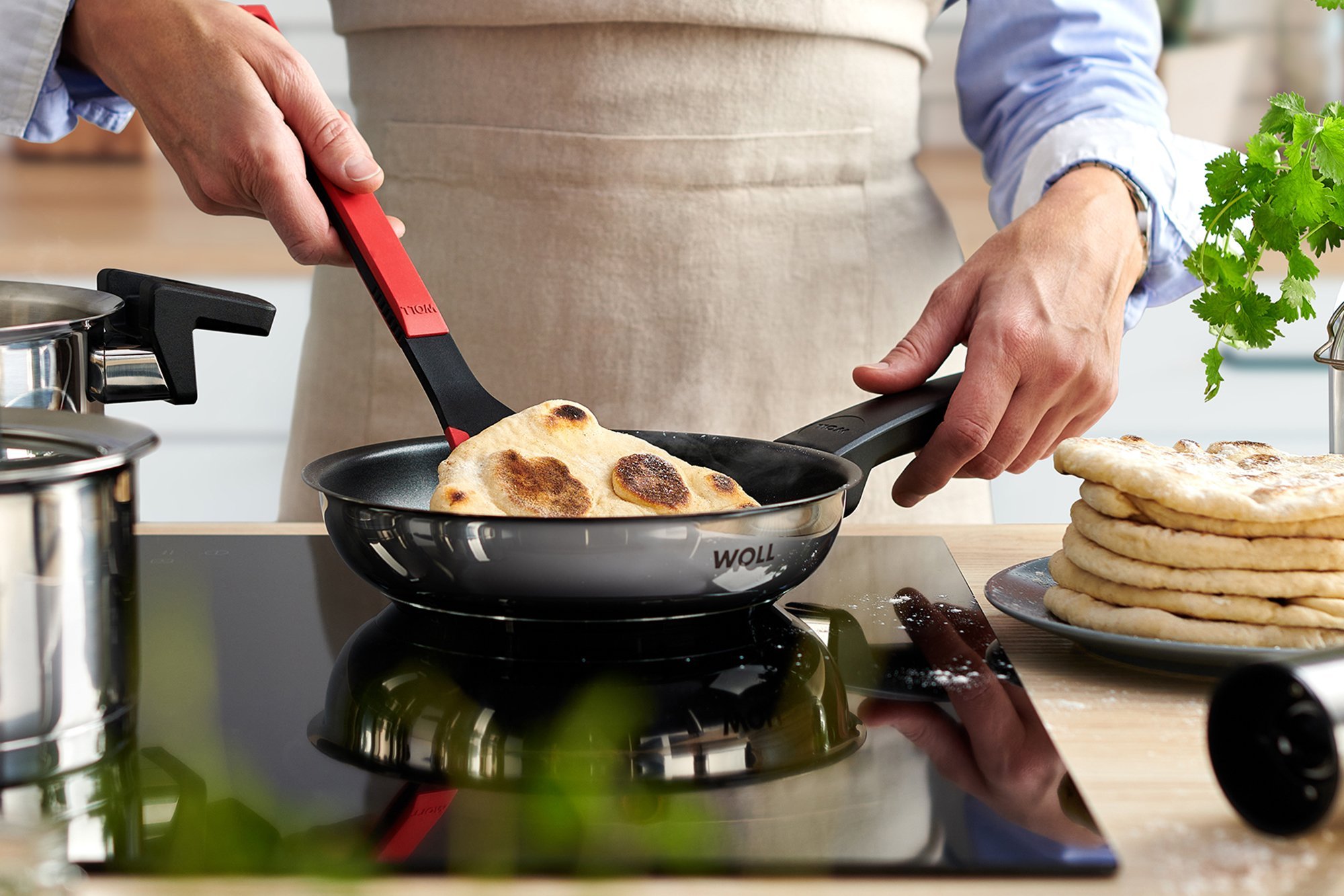 In einer runden Concept Pfanne wird ein Fladenbrot mit eeinem Cock it gewendet. Daneben stehen zwei Concept Töpfe.