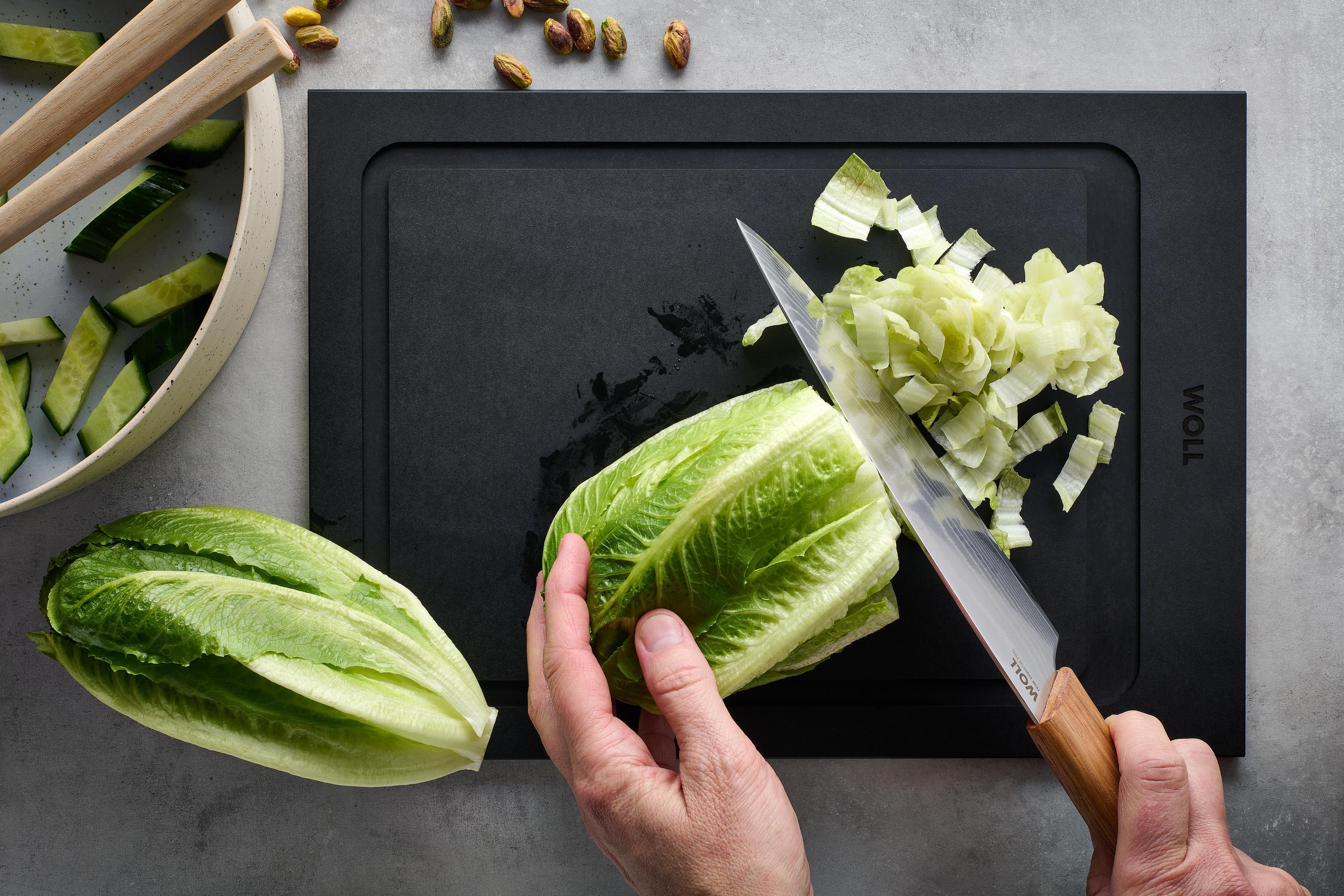 Mit dem Prime Edge Santokumesser wird ein Salatkopf auf einem Schneidebrett kleingeschnitten. 