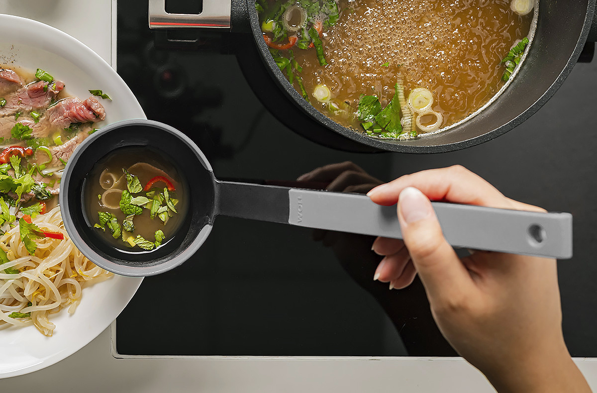 In einem runden Logic Topf befindet sich gekochte Brühe. Mit einer grauen Cock it Schöpfkelle wird die Brühe über die Nudeln im Teller gegossen.