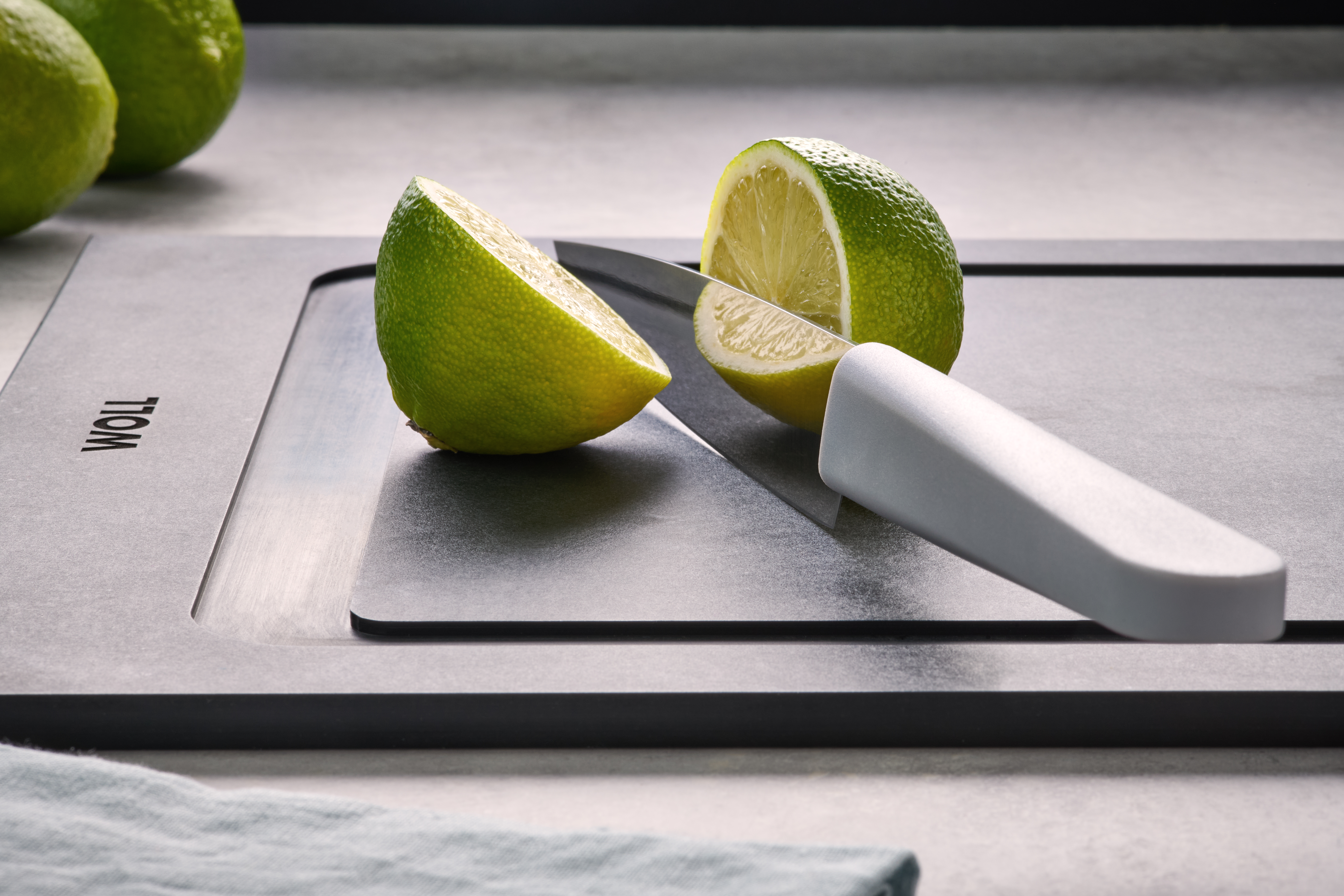 Eine Limette wurde mit einem Cuting Edge Messer auf einem Cut & Serve Schneidebrett halbiert. 