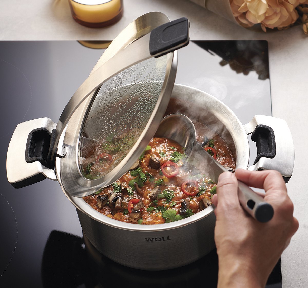 In einem runden Concept Pro Kochtopf wird ein dampfendes Gericht zubereitet. Der Glasdeckel wurde in den Griffeinraster gestellt, sodass er offen bleibt.