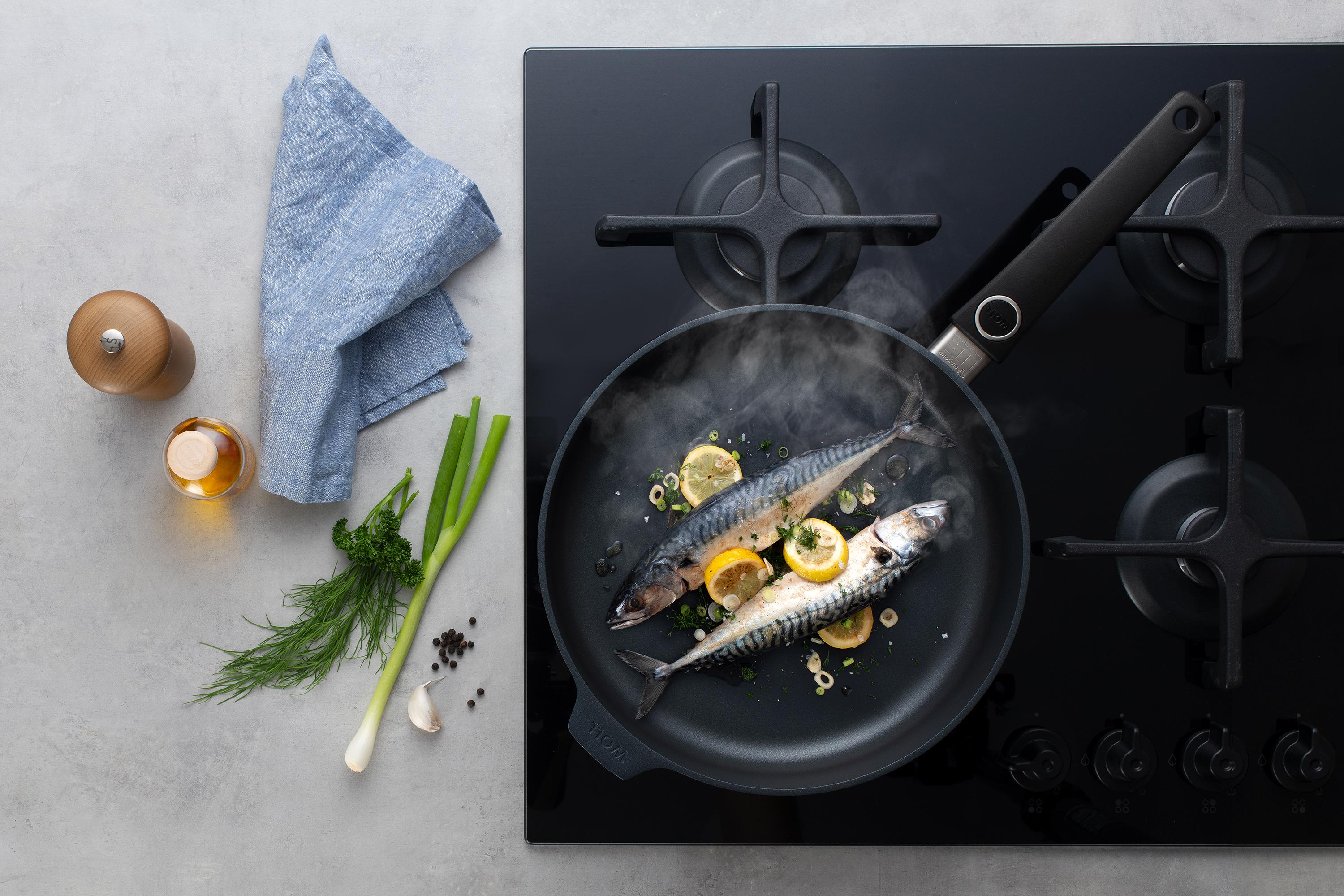 In einer runden Diamond Lite Pfanne wird Fisch mit Zitrone und Frühlingszwiebeln zubereitet. Am Glasdeckel hat sich Kondenswasser gebildet.